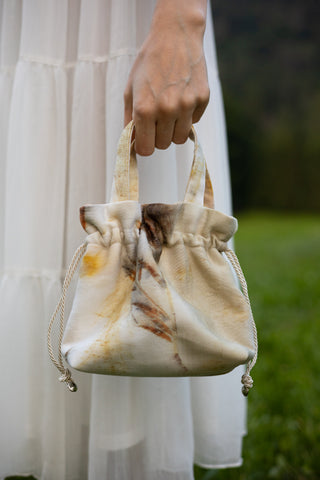 Borsa mini artigianale in tessuto riciclato con stampa botanica da foglie di eucalipto, chiusura a coulisse e manici da infilare al polso; elegante, sostenibile e ideale per ogni occasione.